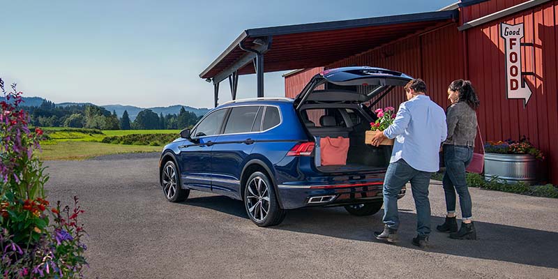 A man and woman loading items in the trunk of a Volskwagen Tiguan.